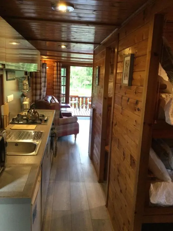 a kitchen with wooden walls and a counter top at RIVERSIDE LODGE RETREAT in Aviemore