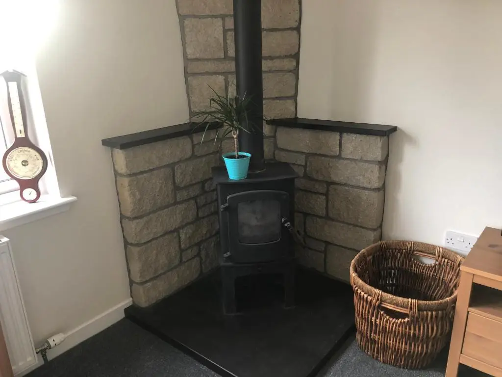 a room with a brick fireplace with a black stove at River Ness View in Inverness