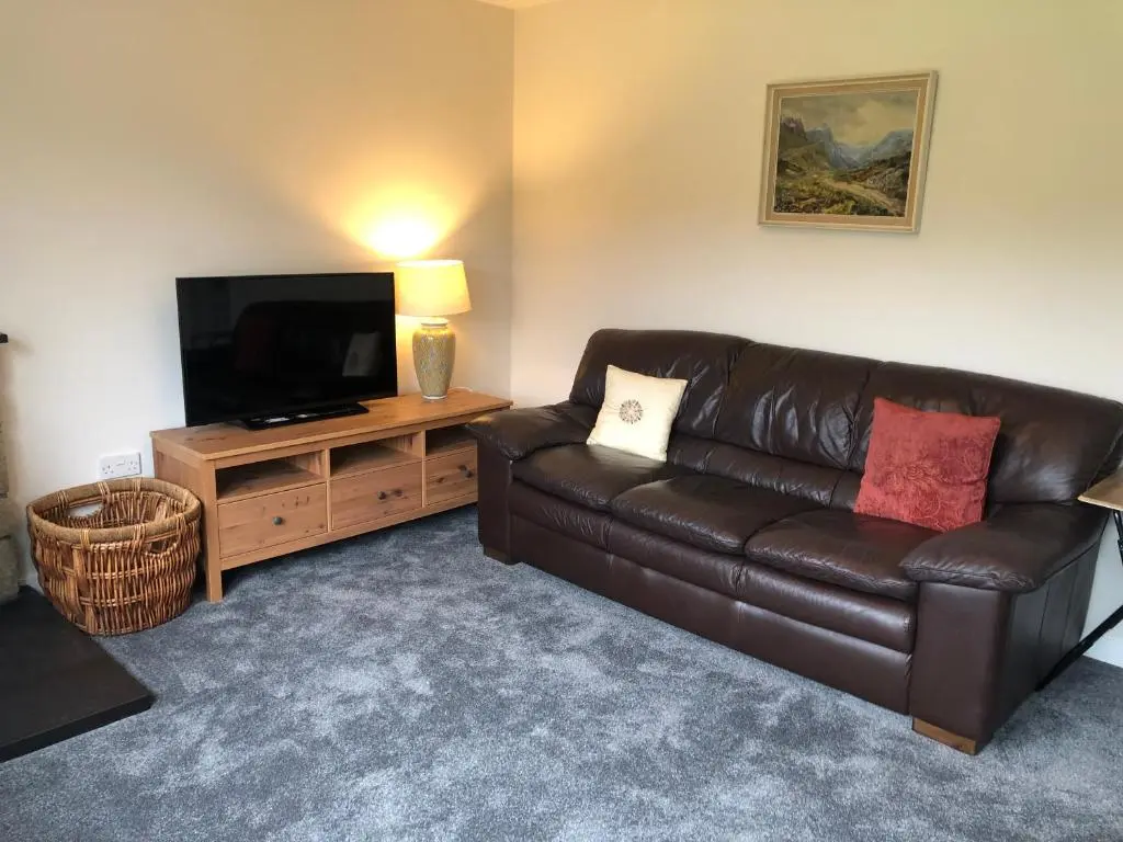 a living room with a leather couch and a flat screen tv at River Ness View in Inverness