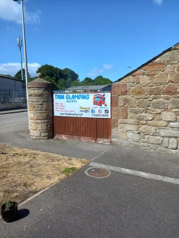 a sign on a brick wall with a fence at Half Pint in Tain