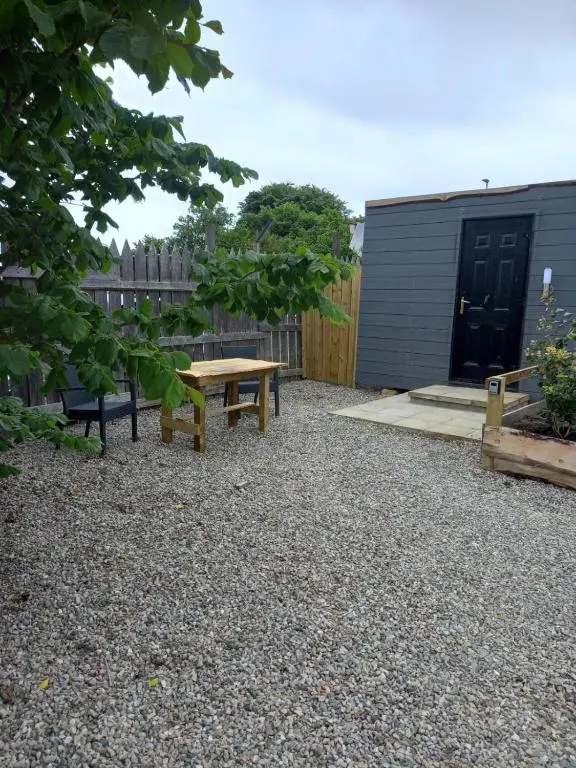 a picnic table and a bench in a gravel yard at Wee Shot in Tain