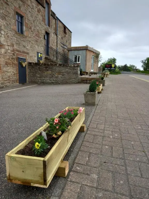a row of wooden planters with flowers on a street at Wee Shot in Tain