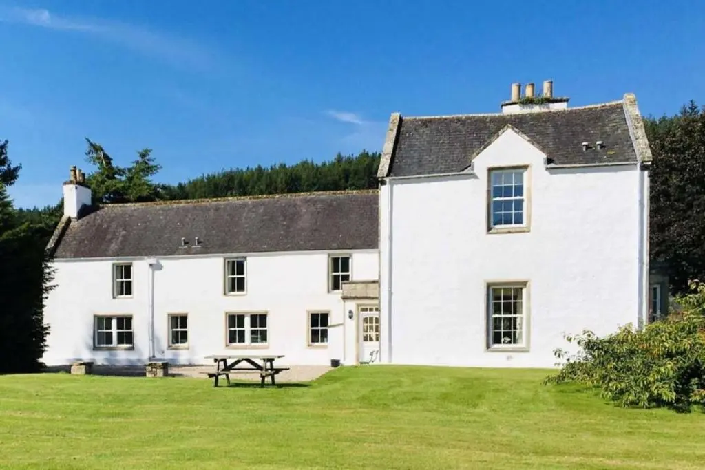 a large white house with a picnic table in the yard at Garbity Farmhouse - beautiful 6-bedroom Farmhouse with open fires in Fochabers