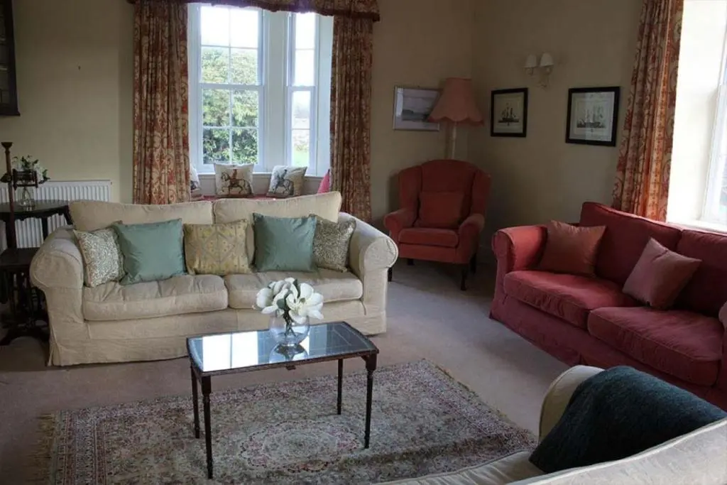 a living room with two couches and a table at Garbity Farmhouse - beautiful 6-bedroom Farmhouse with open fires in Fochabers
