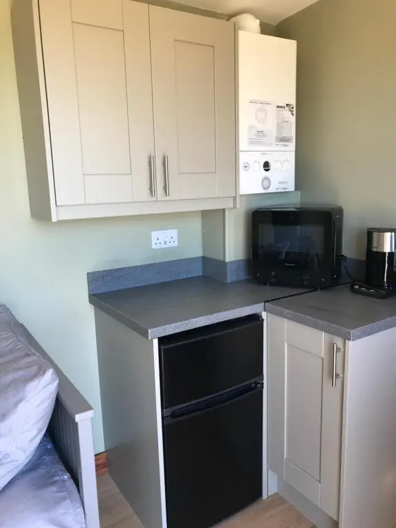 a small kitchen with a microwave and a black dishwasher at Ben Klibreck, Ben Hope, Ben Hee in Torroboll