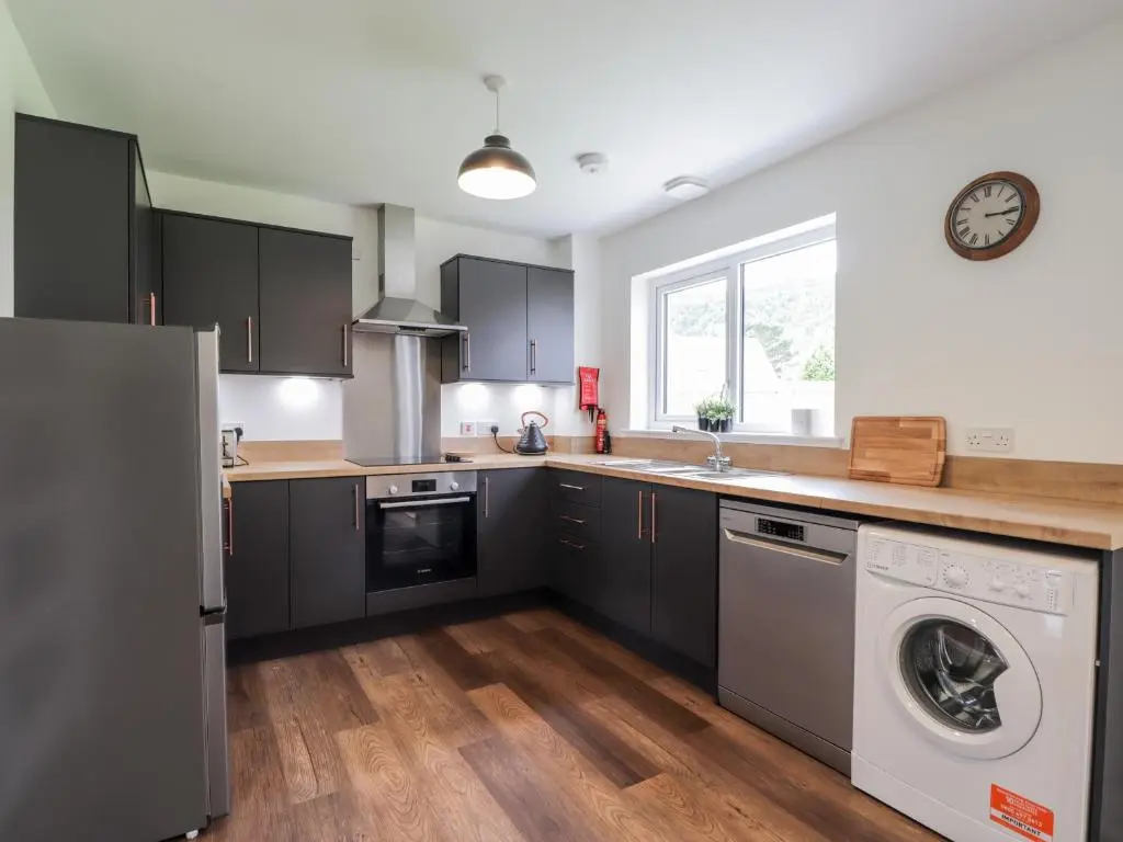 a kitchen with black cabinets and a washer and dryer at 6 Bynack More in Aviemore