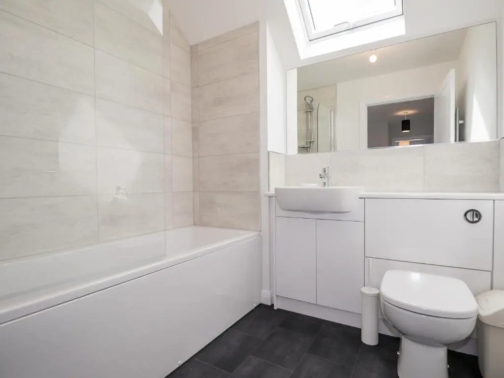 a white bathroom with a tub and a toilet and a sink at 6 Bynack More in Aviemore