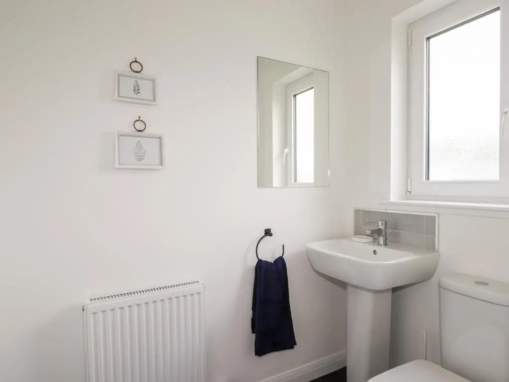 a white bathroom with a sink and a toilet at 6 Bynack More in Aviemore