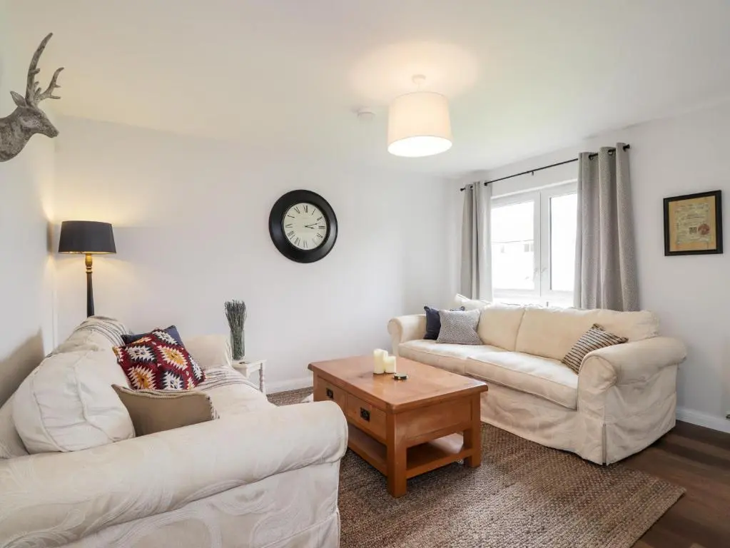 a living room with two white couches and a table at 6 Bynack More in Aviemore