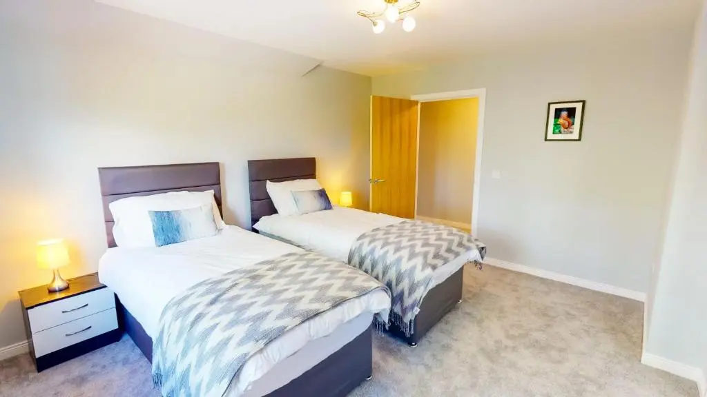 a bedroom with two beds and a night stand with two lamps at Braeside - Family home in Nethy Bridge in Nethy Bridge