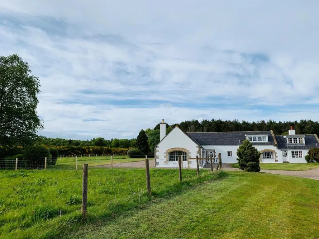 a white house with a fence in front of a field at Bruntlands Steading in Fochabers