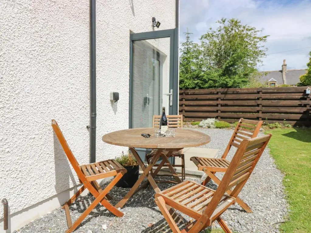 a wooden table and chairs on a patio at Kilmuir Cottage in Tomintoul