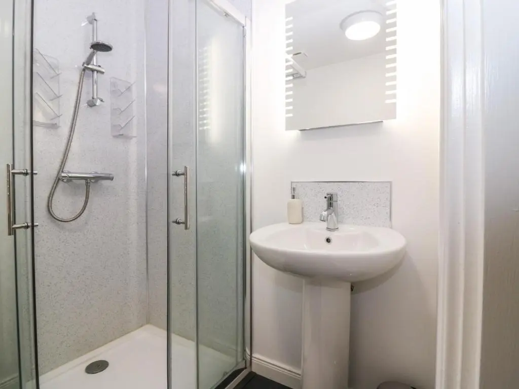 a white bathroom with a sink and a shower at Kilmuir Cottage in Tomintoul