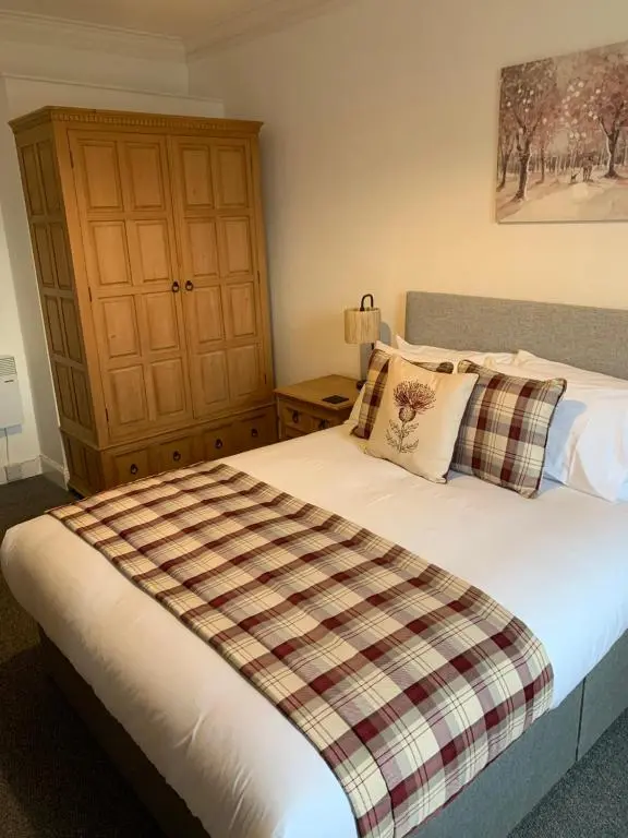 a bedroom with a bed with a plaid blanket at Caithness Stone house in Wick