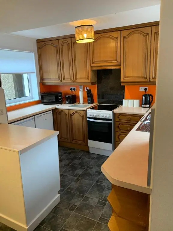a kitchen with wooden cabinets and a white stove top oven at Caithness Stone house in Wick