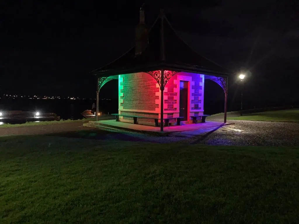 a gazebo lit up in purple and green at night at Caithness Stone house in Wick