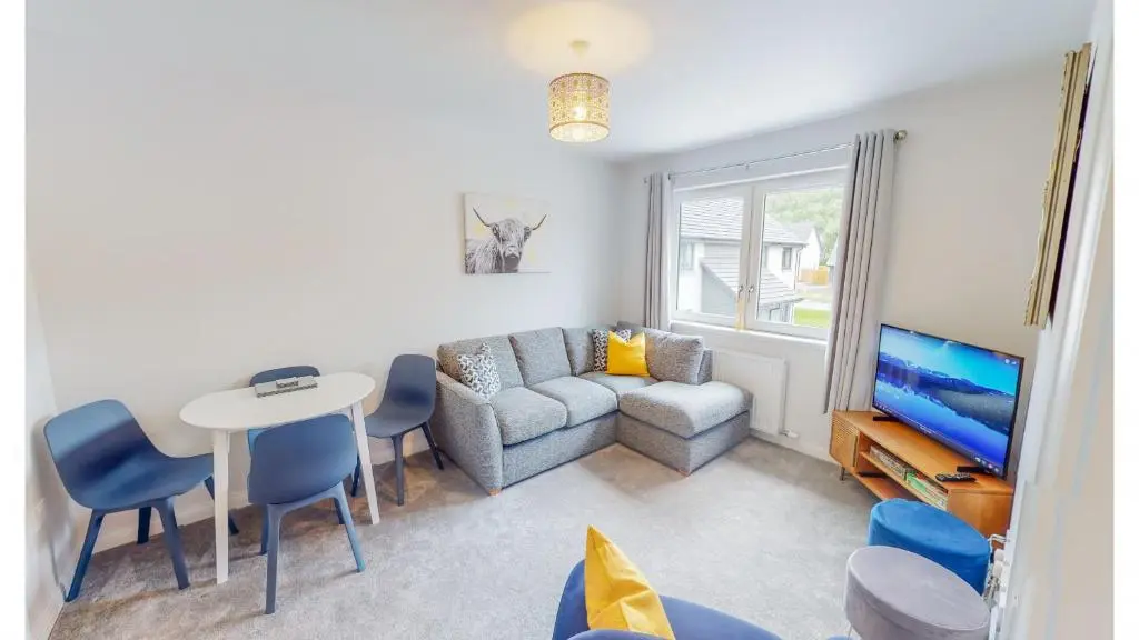 a living room with a couch and a table and a tv at 10 Bynack House in Aviemore