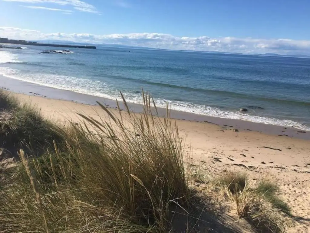 a beach with the ocean and some grass at Garbity Cottage in Fochabers