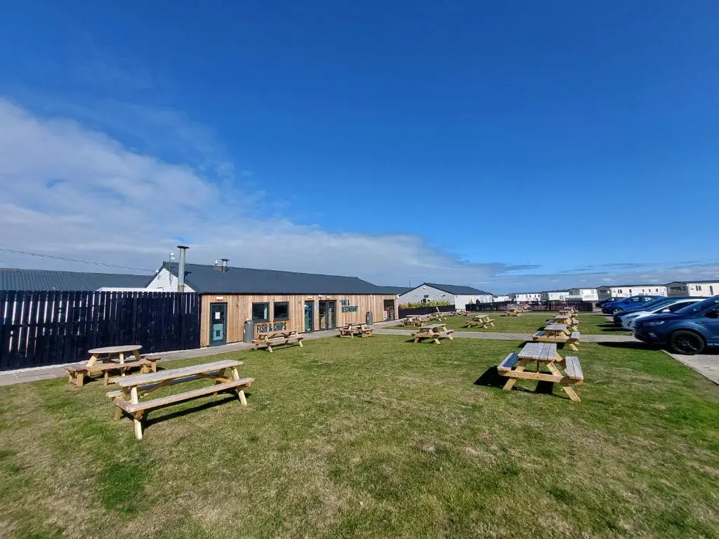 a group of picnic tables in a field near the water at Aurora Way 81 in Lossiemouth