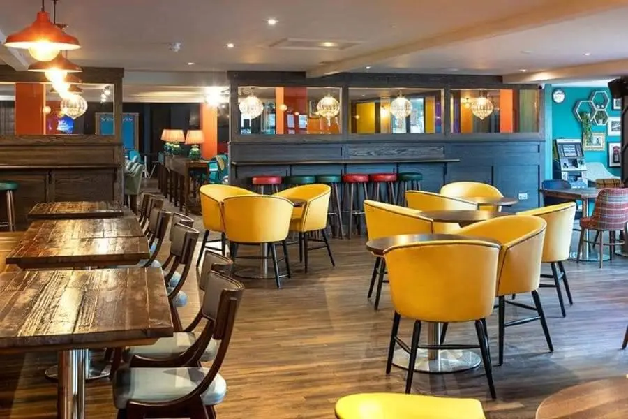 a restaurant with wooden tables and yellow chairs at Aurora Way 81 in Lossiemouth