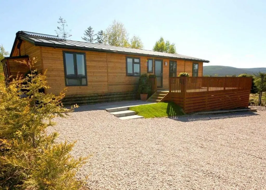 a small wooden house with a fence in front of it at Castlewood Lodges in Strachan