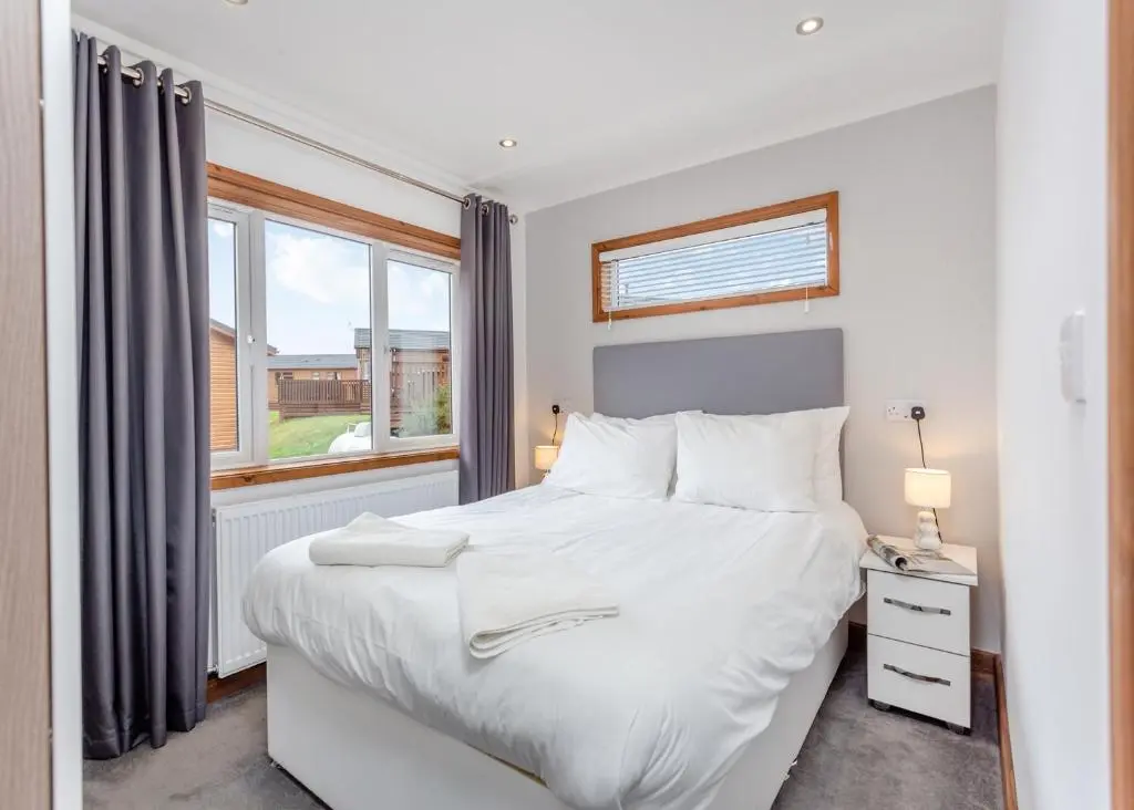 a bedroom with a white bed and a window at Castlewood Lodges in Strachan