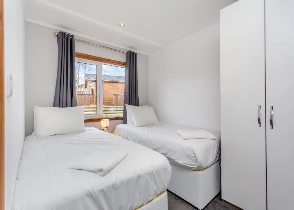 two beds in a room with a window at Castlewood Lodges in Strachan
