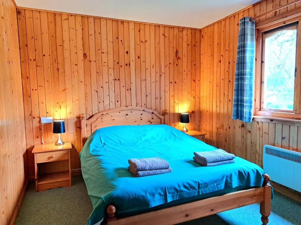a bedroom with a bed in a wooden wall at Plodda Lodge at Lochletter Lodges in Drumnadrochit