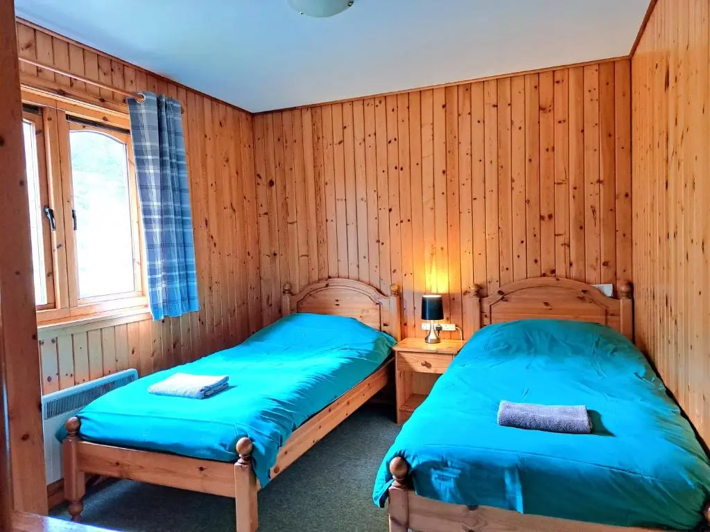 two beds in a room with wooden walls at Plodda Lodge at Lochletter Lodges in Drumnadrochit
