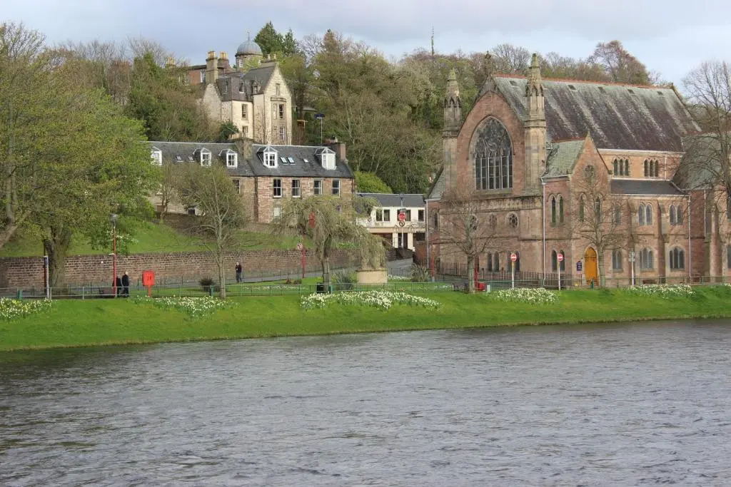a large building next to a body of water at Ness View Apartment in Inverness