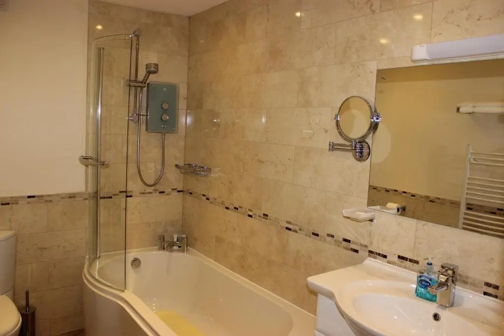 a bathroom with a tub and a sink and a mirror at Ness View Apartment in Inverness