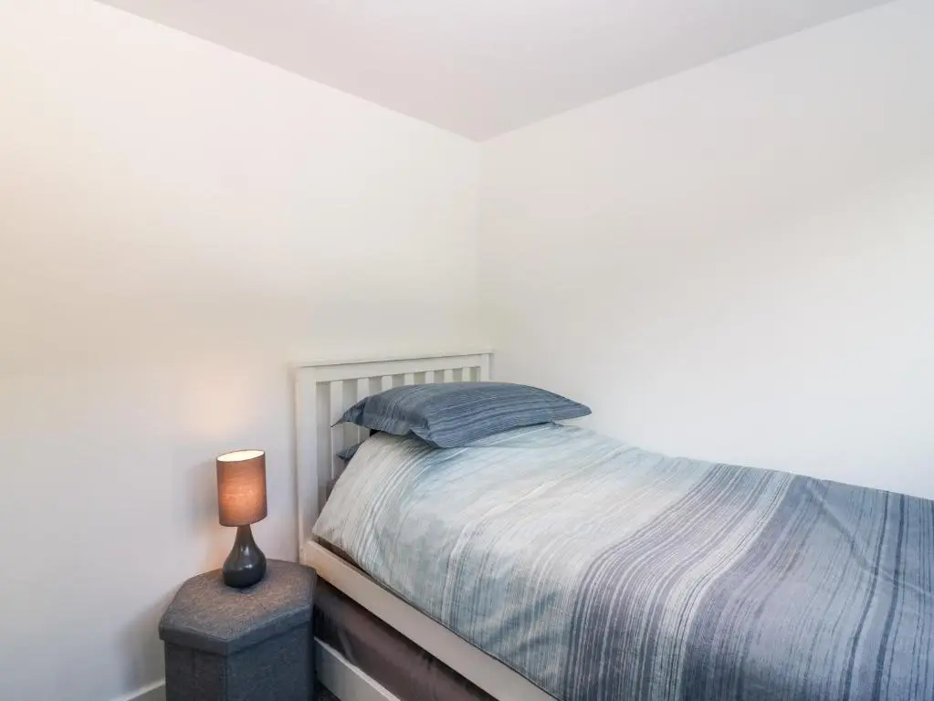 a white bedroom with a bed and a lamp at Dolphin Cottage in Banff