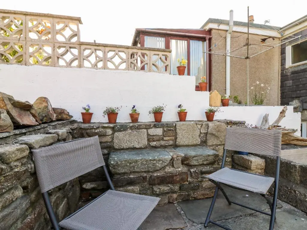 two chairs sitting on a stone wall with potted plants at Dolphin Cottage in Banff