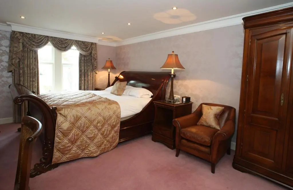 a bedroom with a bed and a chair at Mansion House Hotel in Elgin