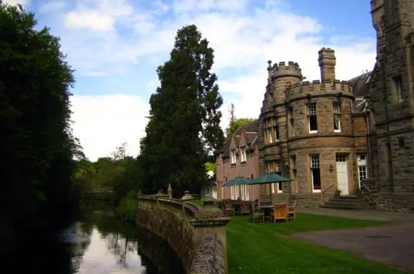 an old building with a bridge next to a river at Mansion House Hotel in Elgin