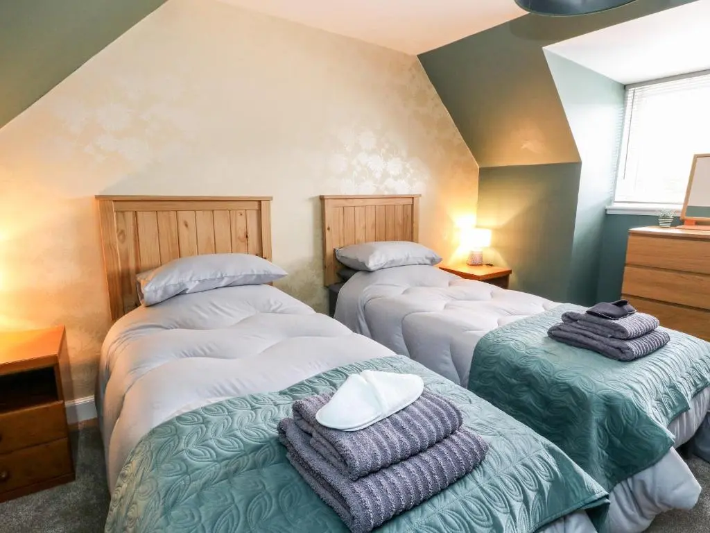 a bedroom with three beds with towels on them at Ulla Dhu in Nethy Bridge