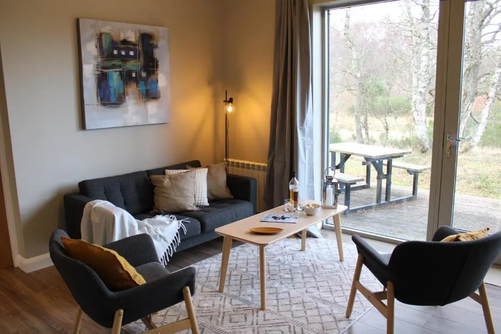 a living room with a couch and a table at Betula Chalet \u2013 coast & country in the Highlands in Nairn