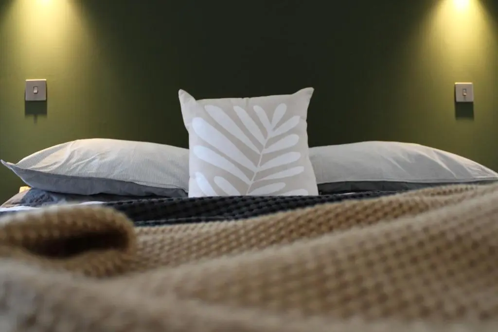 a bed with a white pillow and pillows on it at Betula Chalet \u2013 coast & country in the Highlands in Nairn