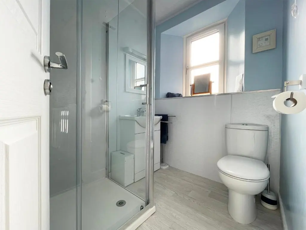 a bathroom with a toilet and a glass shower at Harbour Street in Portmahomack