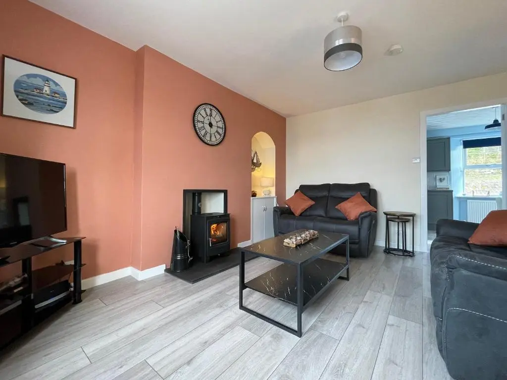 a living room with a couch and a clock on the wall at Harbour Street in Portmahomack