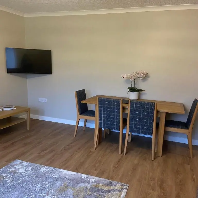 a dining room with a table and chairs and a tv at Cathwill - Cosy 4 Star Cottage - Cairngorm National Park in Newtonmore