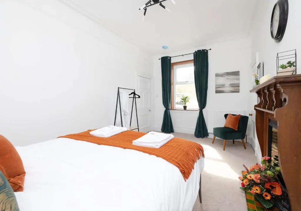 a white bedroom with a bed and a window at Aurora House Hot Tub & Sea View in Buckie