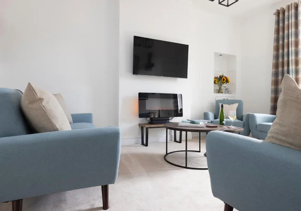a living room with two blue chairs and a tv at Aurora House Hot Tub & Sea View in Buckie
