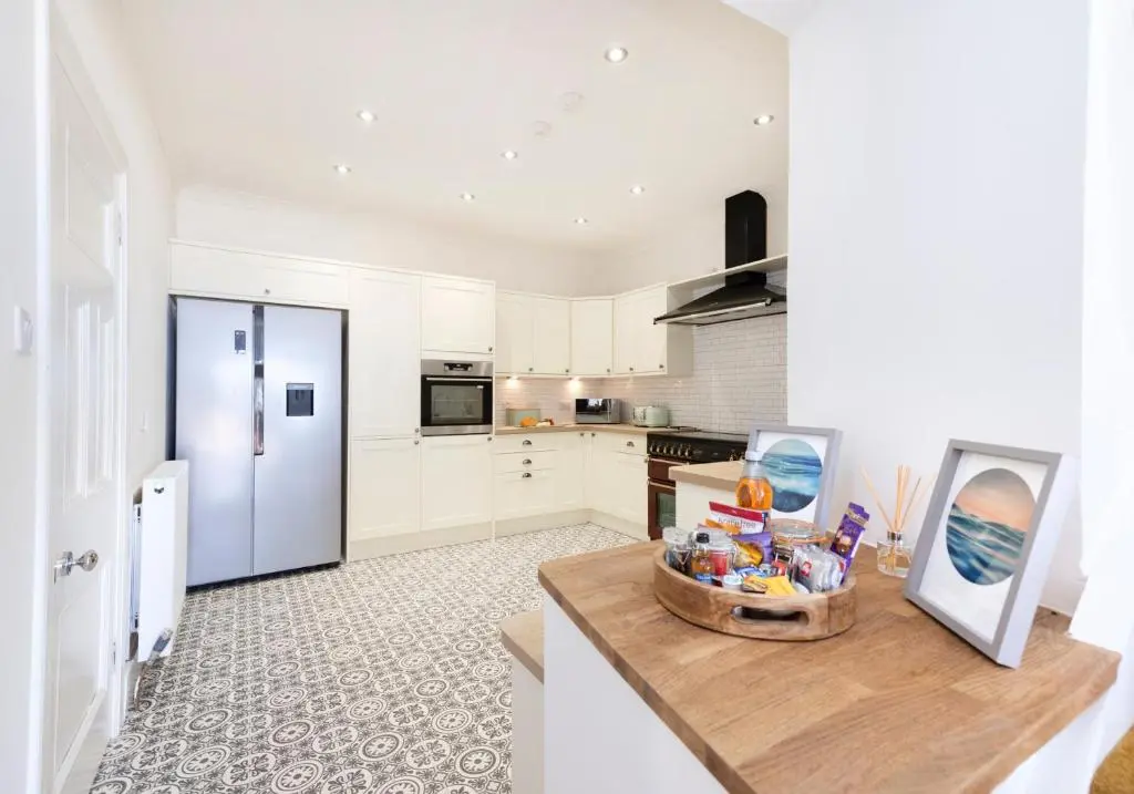 a kitchen with white cabinets and a counter with a table at Aurora House Hot Tub & Sea View in Buckie