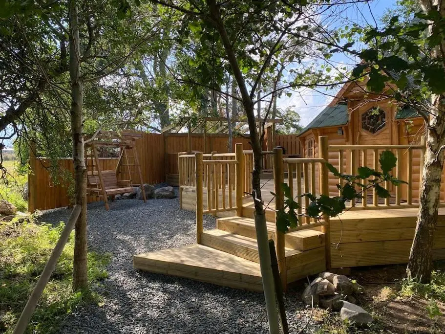 a wooden playground in a backyard with a wooden house at Craigshannoch Luxury 1 bed woodland lodge hot tub in Kintore