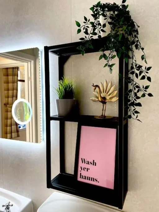 a black shelf with a sign in front of a mirror at *Cool, cosy cottage in the heart of the Highlands* in Kincraig