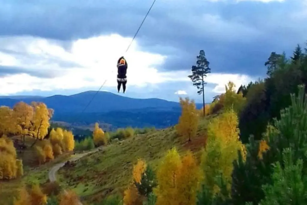 a person on a zip line in the mountains at *Cool, cosy cottage in the heart of the Highlands* in Kincraig