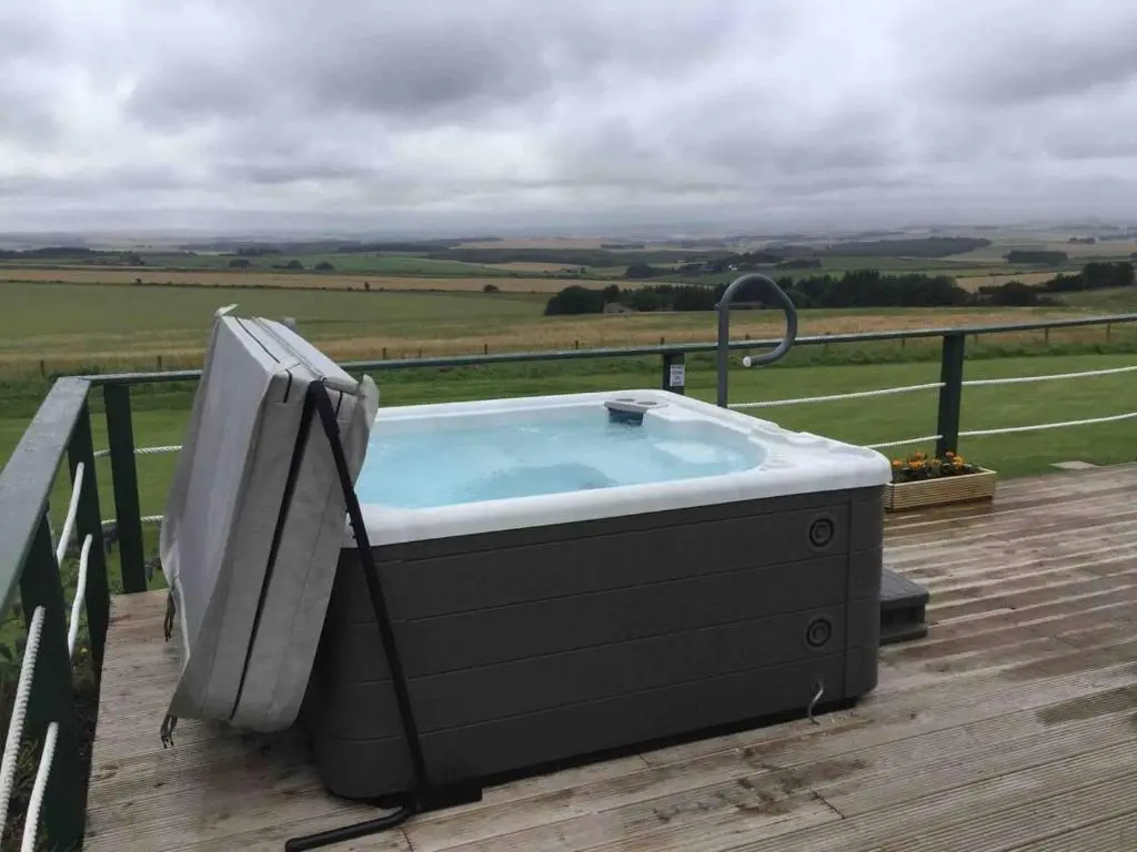 a bath tub sitting on a deck with a television at Green Yurt with Hot Tub - Sleeps 3 Parking & Pets in Turriff