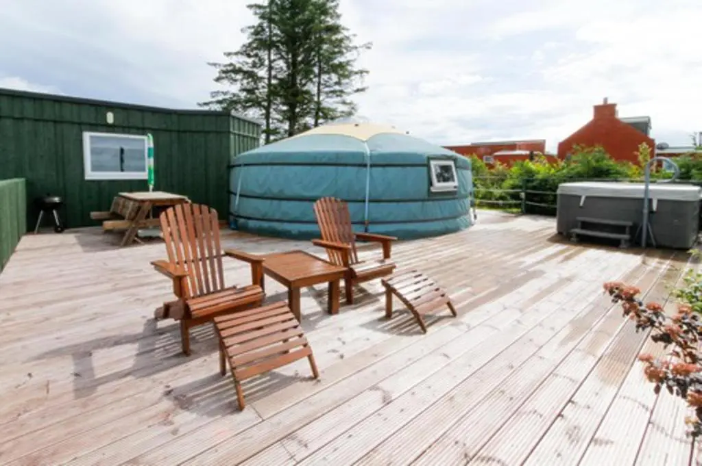 a deck with chairs and a table and a yurt at Green Yurt with Hot Tub - Sleeps 3 Parking & Pets in Turriff