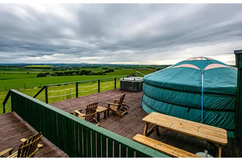 a blue tent on a deck with a table and chairs at Orange Yurt with Hot Tub- Sleeps 3 Parking & Pets in Turriff